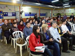 Moradores ouvem a apresentação da sistemática da reunião, na primeira fila, o secretário da educação Roque Mattei e outros representantes da secretaria